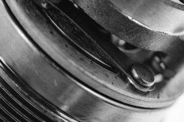 Gri tonlamada vidalara yakın çekim karmaşık yuvarlak metal mekanik cihaz. Kopyalama alanı ile otomatik parçanın tek renkli arka planı.