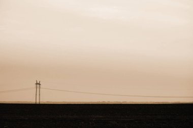 Gökyüzü yakın çekim arka planda güç hatları. Sepya tonlarında kopya alanı ile elektrik direği silueti. Yerden yüksek voltajlı kablolar. Tek renkli elektrik endüstrisi.