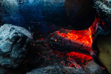 Yanan kütükler canlı ateşte yandı. Kamp ateşi turuncu alev ile atmosferik arka plan. Kopya alanı ile içeriden şenlik ateşi hayal edilemez ayrıntılı görüntü. Duman ve kül kasırgası yakın.