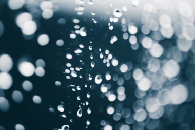 Yağmur damlalarıyla kirli pencere camı. Bokeh yağmur damlaları ile atmosferik mavi arka plan. Damlacıklar ve lekeler kapanır. Kopyalama alanı ile makroda ayrıntılı saydam doku. Yağmurlu hava.