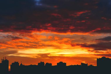 Harika varirenkli canlı ateşli şafak ile Cityscape. İnanılmaz dramatik çok renkli bulutlu gökyüzü. Şehir binalarının karanlık siluetleri. Bulutlu havalarda gün doğumunun atmosferik arka planı. Kopyalama alanı.