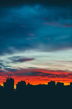 Harika varirenkli canlı şafak ile Cityscape. Şehir binalarının karanlık siluetleri üzerinde inanılmaz dramatik çok renkli bulutlu gökyüzü. Bulutlu havalarda gün doğumunun atmosferik arka planı. Kopyalama alanı.