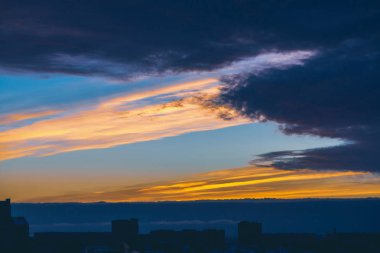 Harika varirenkli canlı şafak ile Cityscape. Şehir inşa çatıları karanlık siluetleri üzerinde Inanılmaz dramatik mavi bulut gökyüzü. Bulutlu havalarda turuncu gündoğumu atmosferik arka plan. Kopyalama alanı