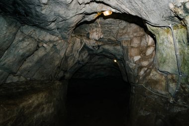 Güzel bir mağara. Karanlık zindandan manzara. Mağaranın dokulu duvarları. Yeraltı tünelinin arka plan görüntüsü. Mağaranın içinde nem var. Geziler için mağara içinde Aydınlatma.
