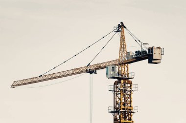 Soluk tonlarda gökyüzüne karşı büyük kule vinç. Kopya alanı ile inşaat ekipmanları yakın çekim arka plan. Şehrin inşası.