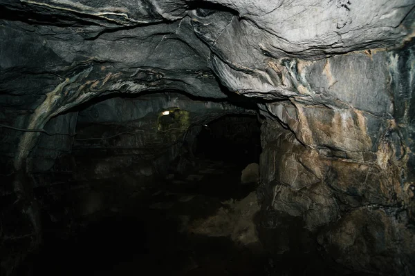 Beautiful cave. View from inside dark dungeon. Textured walls of cave. Background image of underground tunnel. Dampness inside cave. Lighting inside cave for excursions.