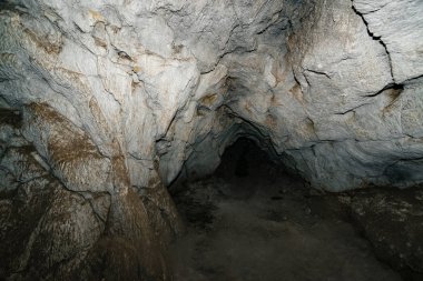 Güzel bir mağara. Karanlık zindandan manzara. Mağaranın dokulu duvarları. Yeraltı tünelinin arka plan görüntüsü. Mağaranın içinde nem var. Tünelin sonundaki ışık.