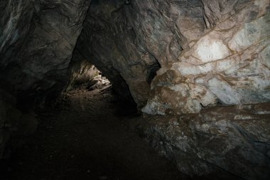 Güzel bir mağara. Karanlık zindandan manzara. Mağaranın dokulu duvarları. Yeraltının arka plan görüntüsü. Mağaranın içinde nem var. Tünelin sonundaki ışık.