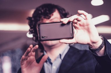 İş adamı akıllı telefon ekranına bakıyor. Adam cep telefonunun arkasına saklanıyor. Macenta sesi.