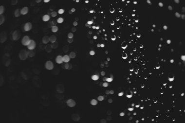 Yağmur damlalarıyla kirli pencere camı. Bokeh yağmur damlaları ile atmosferik tek renkli koyu arka plan. Damlacıklar ve lekeler kapanır. Makroda ayrıntılı saydam doku. Kopya alanı. Yağmurlu hava.