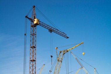 Mavi gökyüzüne karşı büyük kule vinçler. Kopyalama alanı ile yakın çekim inşaat ekipmanları arka plan görüntüsü. Şehrin inşası.