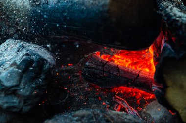 Yanan kütükler canlı ateşte yandı. Kamp ateşi turuncu alev ile atmosferik arka plan. Kopya alanı ile içeriden şenlik ateşi hayal edilemez ayrıntılı görüntü. Duman ve kül kasırgası yakın.