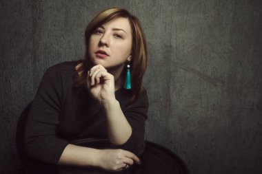 Gri stüdyo arka planda ellerde turkuaz küpe ve vinil kayıt ile güzel şık pensive kız Vintage portre.