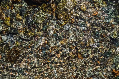 Şeffaf derenin taşlı alt kısmındaki ayrıntılı doku yakın. Dağ deresitemiz su. Kopya alanı ile nehir deresinde pürüzsüz taşların renkli arka planı.