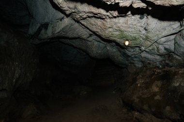 Güzel bir mağara. Karanlık zindandan manzara. Mağaranın dokulu duvarları. Yeraltı tünelinin arka plan görüntüsü. Mağaranın içinde nem var. Geziler için mağara içinde Aydınlatma.