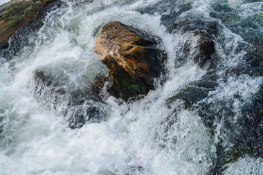 Dağ Deresi'ne yakın çekimde büyük kayalar. Kopya alanı ile hızlı nehir Rapids. Köpüklü su akıntısı. Isldeki taşların yanında hızlı akış. Temiz su dalgalarının arka planı. Dere parlak dere doğal doku
