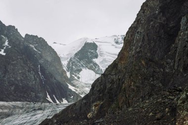 Dağ lık dağda kar. Bulutlu gökyüzü altında atmosferik karlı sırt. Bulutlu havalarda harika dev kayalar. Dağlarda yükseke tırmanın. Yaylaların görkemli doğasının inanılmaz minimalist manzarası.