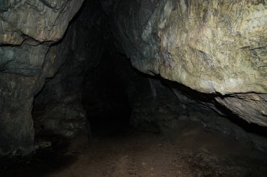 Güzel bir mağara. Karanlık zindandan manzara. Mağaranın dokulu duvarları. Yeraltı tünelinin arka plan görüntüsü. Mağaranın içinde nem var. Tünelin sonundaki ışık.