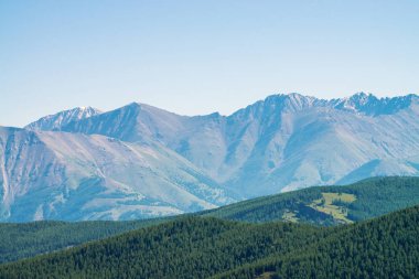 Dev dağlar ve ormanile tepelerüzerinde buzullar. Mavi berrak gökyüzünün altında karlı bir sırt. Dağlık bölgelerde kar zirvesi. Donmuş toprak, kalıcı soğuk. İnanılmaz atmosferik minimalist dağ manzarası.