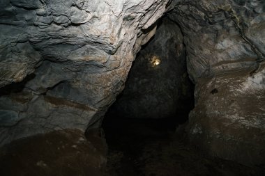 Güzel bir mağara. Karanlık zindandan manzara. Mağaranın dokulu duvarları. Yeraltı tünelinin arka plan görüntüsü. Mağaranın içinde nem var. Geziler için mağara içinde Aydınlatma.