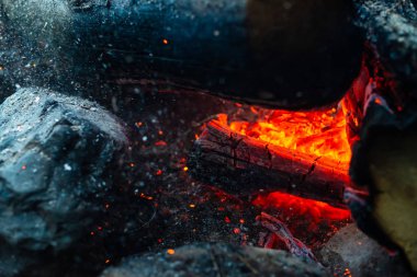 Yanan kütükler canlı ateşte yakılır. Kamp ateşi turuncu alev ile atmosferik arka plan. Kopya alanı ile içeriden şenlik ateşi hayal edilemez ayrıntılı görüntü. Havada duman ve parlayan közler.