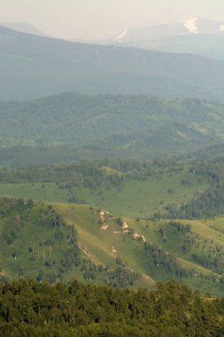 Arka planda büyük tepeler ve kar dağları ile güzel dağ yeşilmanzara. Yeşilliküstünde mavi gökyüzü. Huzur ve huzur.