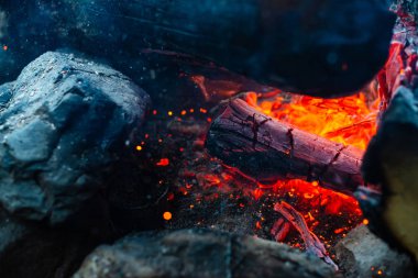 Yanan kütükler canlı ateşte yakılır. Kamp ateşi turuncu alev ile atmosferik arka plan. Kopya alanı ile içeriden şenlik ateşi hayal edilemez ayrıntılı görüntü. Havada duman ve parlayan közler.