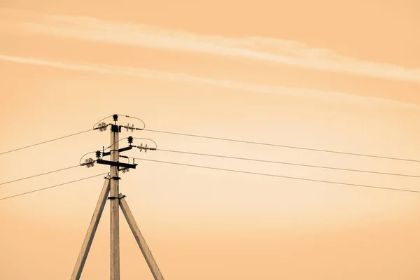 Power lines on background of sky close-up. Electric hub on pole in monochrome. Electricity equipment with copy space. Wires of high voltage in sky. Electricity industry. Sepia tone.