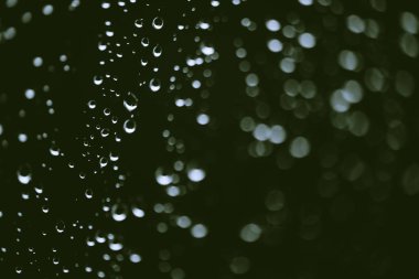Yağmur damlalarıyla kirli pencere camı. Bokeh yağmur damlaları ile atmosferik yeşil arka plan. Damlacıklar ve lekeler kapanır. Kopyalama alanı ile makroda ayrıntılı saydam doku. Yağmurlu hava.