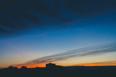 Harika varirenkli canlı şafak ile Cityscape. Şehir inşa çatıları karanlık siluetleri üzerinde Inanılmaz dramatik mavi bulut gökyüzü. Bulutlu havalarda turuncu gündoğumu atmosferik arka plan. Kopyalama alanı