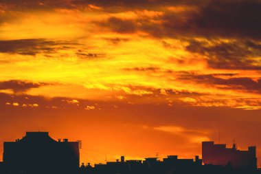 Cityscape canlı ateşli şafak ile. İnanılmaz sıcak dramatik bulutlu gökyüzü karanlık siluetleri şehir binaların yukarıda. Turuncu güneş ışığı. Gündoğumu bulutlu havalarda atmosferik arka plan. Kopya alanı.