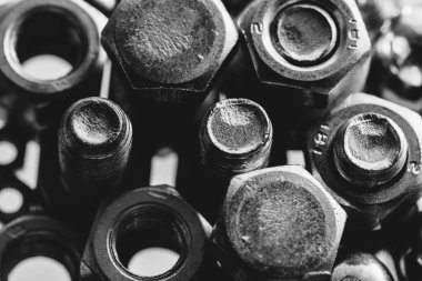 Cıvata ve somunların art monokrom arka plan arka ışıkta kapatın. Makroda küçük bağlantı elemanları.