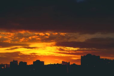 Cityscape canlı ateşli şafak ile. İnanılmaz sıcak dramatik bulutlu gökyüzü karanlık siluetleri şehir binaların yukarıda. Turuncu güneş ışığı. Gündoğumu bulutlu havalarda atmosferik arka plan. Kopya alanı.