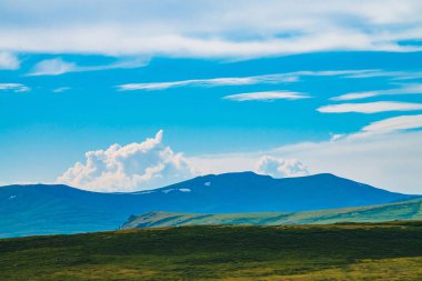 Karla dolu dev dağların muhteşem manzarası. Dağın üzerinde büyük bir bulut. Uçurumun üstündeki büyük kayalık kayalık. Harika vahşi manzara. Görkemli doğanın atmosferik yayla manzarası. Doğal dağ manzarası.