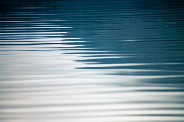 Amazing textured background of calm blue clean water surface. Sunshine in mountain lake close-up. Beautiful ripples on shiny water in sunny day. Wonderful relax texture.