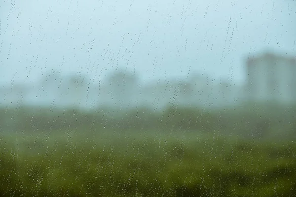 雨の滴と汚れたガラス ボケの緑 空から背景に雨滴 窓の外の街液滴と汚れがクローズアップ マクロ内の詳細な透明テクスチャ — ストック写真