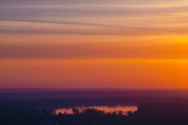 Nehir, çizgili sıcak gökyüzünün altında. Pitoresk bulutların yatay çizgileri. Şafak gökyüzünün yansıması ile gölün atmosferik arka plan görüntüsü.