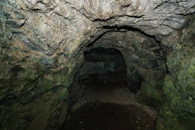 Güzel bir mağara. Karanlık zindandan manzara. Mağaranın dokulu duvarları. Yeraltı tünelinin arka plan görüntüsü. Mağaranın içinde nem var. Tünelin sonundaki ışık.