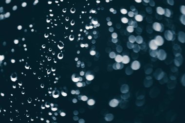 Yağmur damlalarıyla kirli pencere camı. Bokeh yağmur damlaları ile atmosferik mavi arka plan. Damlacıklar ve lekeler kapanır. Kopyalama alanı ile makroda ayrıntılı saydam doku. Yağmurlu hava.