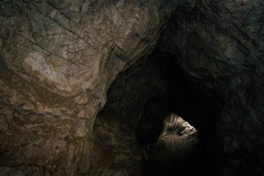 Güzel bir mağara. Karanlık zindandan manzara. Mağaranın dokulu duvarları. Yeraltının arka plan görüntüsü. Mağaranın içinde nem var. Tünelin sonundaki ışık.
