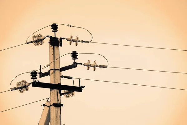 Power lines on background of sky close-up. Electric hub on pole in monochrome. Electricity equipment with copy space. Wires of high voltage in sky. Electricity industry. Sepia tone.