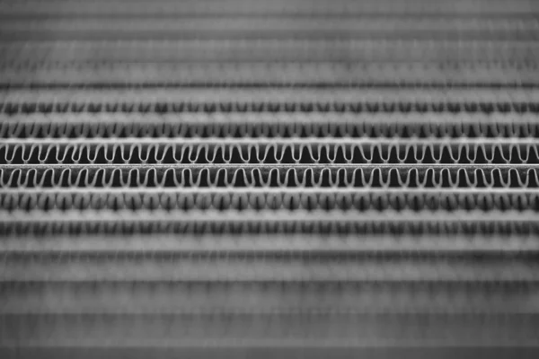 Monochrome background image of automotive radiator close up. Silver background from many duplicate lines.