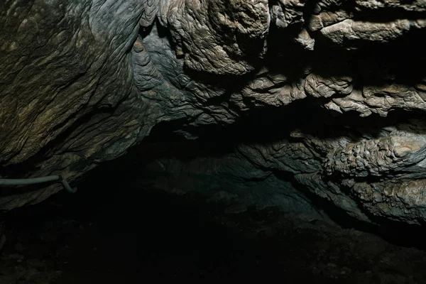 美しい洞窟だ暗いダンジョンの中からの眺め 洞窟のテクスチャードの壁 地下トンネルの背景画像 洞窟内の湿気 小旅行のための洞窟内の照明 — ストック写真