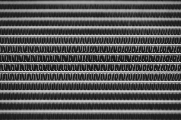 Monochrome background image of automotive radiator close up. Silver background from many duplicate lines.