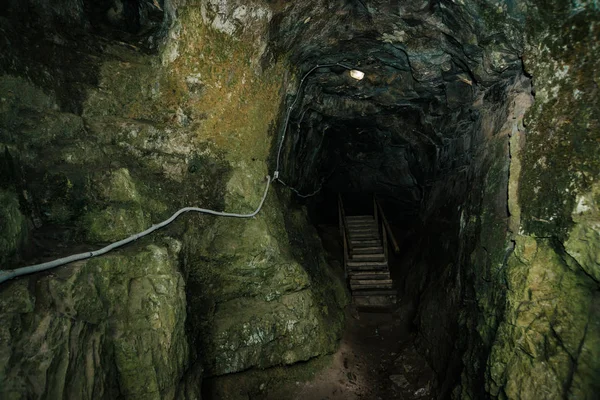 Beautiful cave. View from inside dark dungeon. Textured walls of cave. Background image of underground tunnel. Dampness inside cave. Lighting inside cave for excursions.