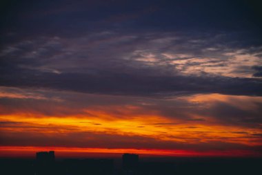 Harika varirenkli ateşli şafak ile Cityscape. İnanılmaz dramatik çok renkli bulutlu gökyüzü. Şehir binası çatılarının karanlık siluetleri. Bulutlu havalarda gün doğumunun atmosferik arka planı. Kopyalama alanı.