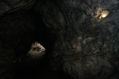 Güzel bir mağara. Karanlık zindandan manzara. Mağaranın dokulu duvarları. Yeraltı tünelinin arka plan görüntüsü. Mağaranın içinde nem var. Geziler için mağara içinde Aydınlatma.