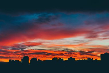 Harika varirenkli canlı şafak ile Cityscape. Şehir binalarının karanlık siluetleri üzerinde inanılmaz dramatik çok renkli bulutlu gökyüzü. Bulutlu havalarda gün doğumunun atmosferik arka planı. Kopyalama alanı.