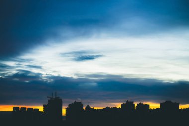 Harika varirenkli canlı şafak ile Cityscape. Şehir binalarının karanlık siluetleri üzerinde Inanılmaz dramatik mavi bulutlu gökyüzü. Bulutlu havalarda turuncu gündoğumu atmosferik arka plan. Kopyalama alanı.