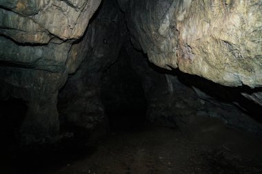 Güzel bir mağara. Karanlık zindandan manzara. Mağaranın dokulu duvarları. Yeraltı tünelinin arka plan görüntüsü. Mağaranın içinde nem var. Tünelin sonundaki ışık.